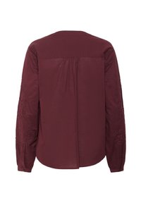 Bordeaux skjorte med lange ærmer, broderede blomsterdetaljer på ærmerne, knapmanchetter, rygplies og glat tekstur.