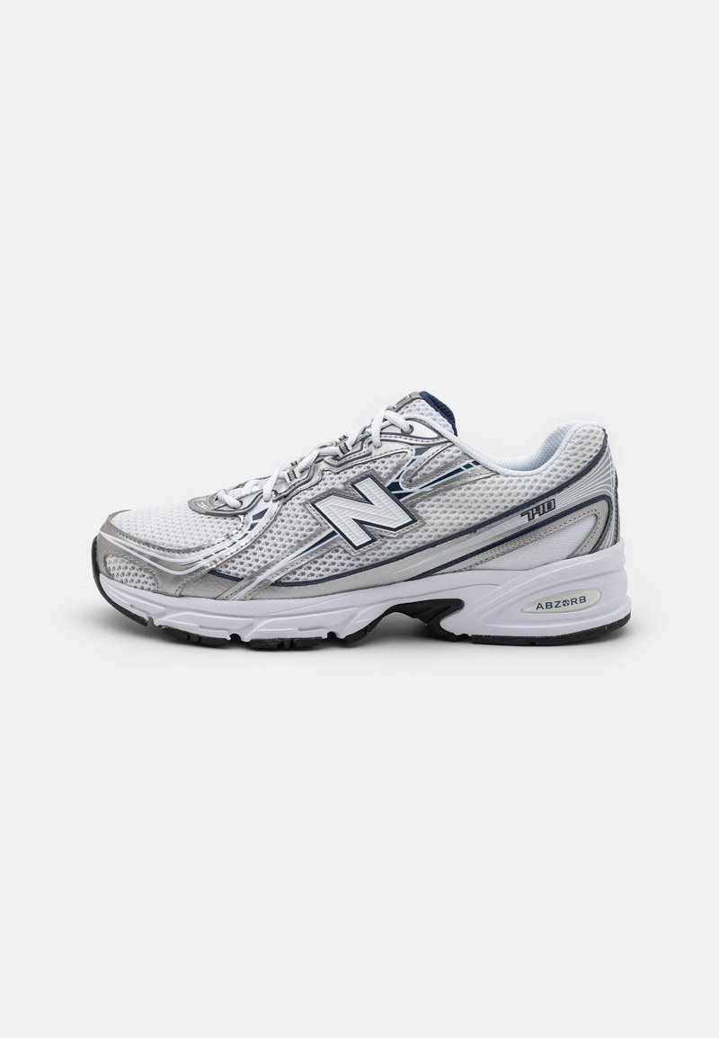 Sapatilha desportiva New Balance com parte superior em malha, predominantemente branca com detalhes em cinzento e azul marinho, apresentando uma sola acolchoada e detalhes texturizados.