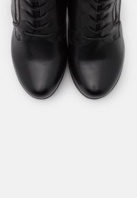 Bottines en cuir noir avec une texture lisse, bout rond et laçage décoratif ; fermeture éclair sur le côté pour un enfilage facile.