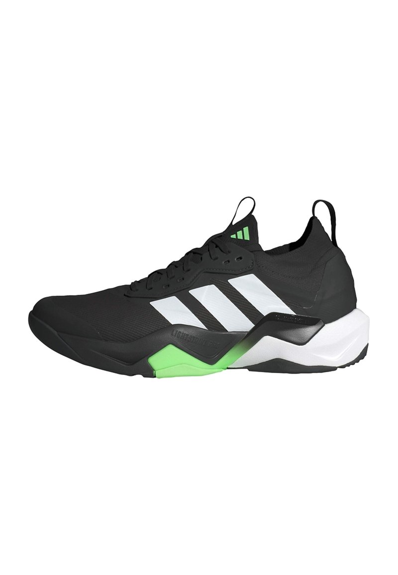 Chaussure de sport noire avec des accents blancs et verts, présentant une tige texturée, un design à lacets et une semelle audacieuse et profilée.