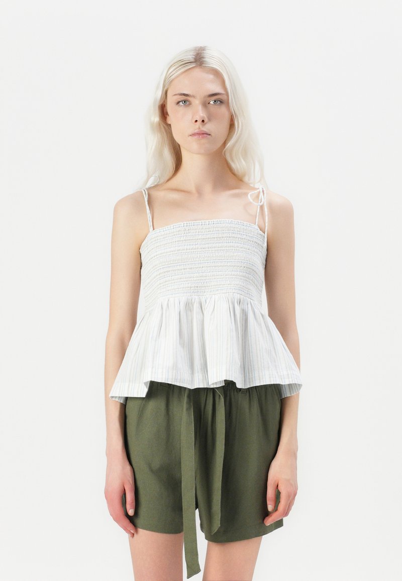 Hvit og stripete peplum-top med tynne stropper, teksturert bodice og samlet nederkant, sammen med grønne shorts med snor.