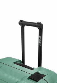 Manico nero retrattile esteso da una valigia verde con texture, dotata di una chiusura e del logo REDOLZ sul tubo del manico.