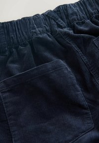 Navy corduroy pants with an elastic waistband and a front pocket, featuring a textured fabric and visible ribbed pattern.