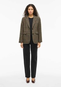 Brown checkered blazer with lapels and two buttons, worn over a black top, paired with black straight-leg pants and burgundy heels.