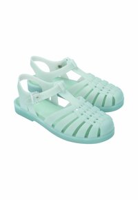 Miętowo-zielone plastikowe sandały z otwartym wzorem, z poziomymi i pionowymi paskami, regulowanym zapięciem na kostce oraz płaską podeszwą.