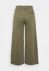 Pantalon large vert olive avec taille élastiquée et une poche passepoilée unique à l'arrière côté droit.