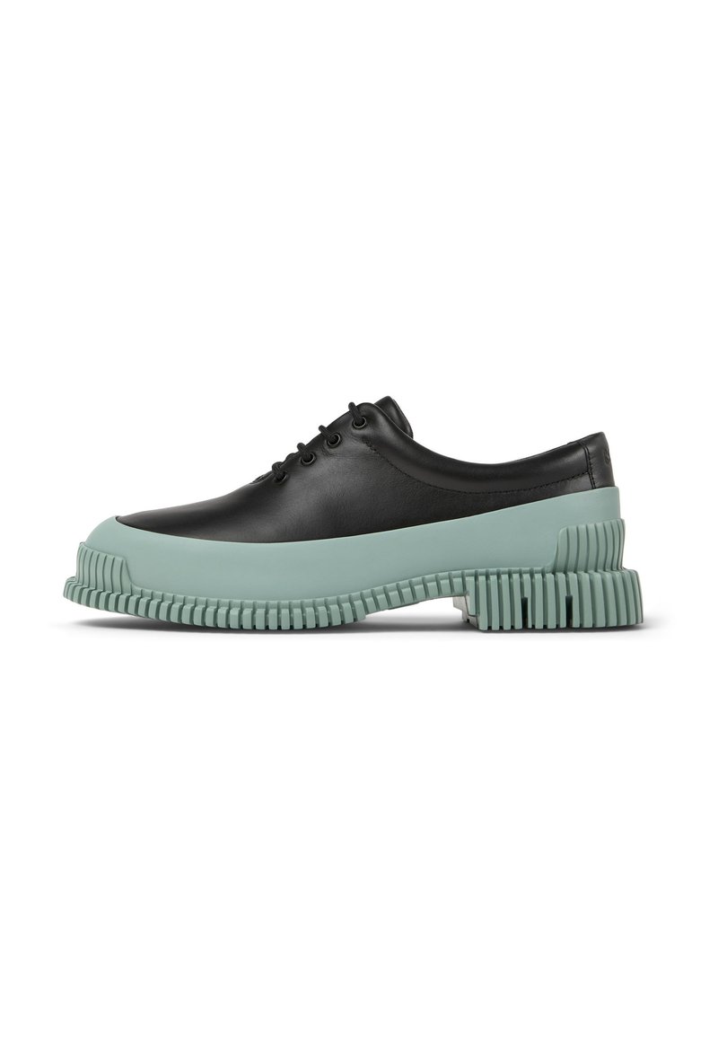 Scarpa nera in pelle con lacci, dotata di suola in gomma verde menta spessa con dettagli scanalati. Il design ha una punta arrotondata e una texture liscia.