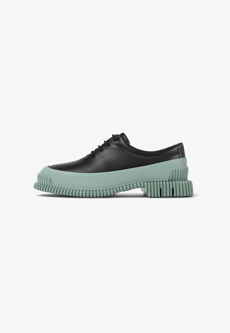 Scarpa nera in pelle con lacci, dotata di suola in gomma verde menta spessa con dettagli scanalati. Il design ha una punta arrotondata e una texture liscia.