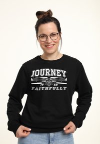Zwarte sweatshirt met witte grafische tekst "JOURNEY" en "FAITHFULLY", met een embleemontwerp. Lange mouwen en een ronde hals.
