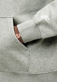 Ανοιχτό γκρι φούτερ με κουκούλα και τσέπη καγκουρό. Διαθέτει ριμπ τελείωμα στα μανίκια και μικρό λευκό λογότυπο Nike στο μανίκι. Απαλό, υφή υφάσματος με υφή.