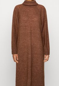 Robe marron en maille avec un col montant, des manches longues et une coupe décontractée. La robe présente un tissu texturé avec un motif subtil sur toute la surface.