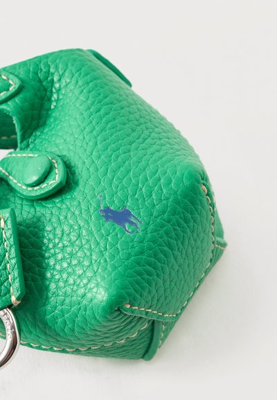 Κοντινή λήψη ενός υφασμάτινου πράσινου δερμάτινου τσαντιού με ορατό ράψιμο και μικρό μπλε λογότυπο παίκτη πόλο στην επιφάνεια.