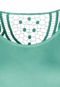 Vihreä tanktoppi, jossa on teksturoitu pitsiselkä, jossa on kuusikulmainen kuvio ja pyöreitä korostuksia. Sujuva kangas ja pyöreä kaula-aukko.