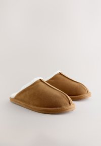 Brązowe zamszowe kapcie z białą futrzaną wyściółką, zaokrąglonym noskiem i miękką podeszwą; bezszwowa konstrukcja z widocznymi przeszyciami jako akcentami.