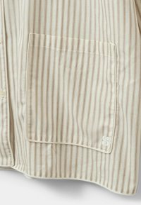 Căma�șă cu guler, cu un croi ajustat, dintr-un material bej cu dungi verticale subțiri de culoare maro deschis și un buzunar pe partea stângă.