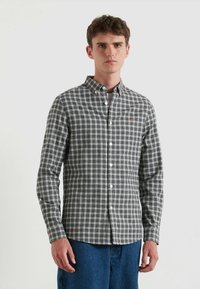 Camicia a righe in plaid nera, grigia e bianca con un piccolo logo arancione sul petto. Presenta un colletto e polsini con un solo bottone.