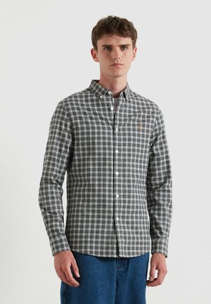 Camicia a righe in plaid nera, grigia e bianca con un piccolo logo arancione sul petto. Presenta un colletto e polsini con un solo bottone.