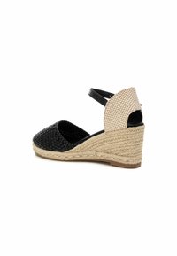 Espadrillas in tessuto nero intrecciato con zeppa piattaforma, dotate di un tacco beige texturizzato e cinturino alla caviglia. Design con punta aperta e dettagli a taglio.