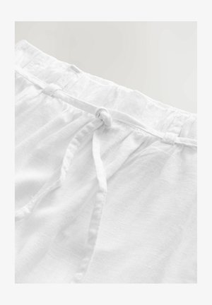 White linen shorts feature a gathered waistband with a drawstring and subtle texture. The fabric appears lightweight and breathable.