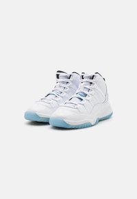 Balti sportiniai bateliai su blizgiu paviršiumi, su paminkštintu krašteliu, tinkliniais liežuviais ir šviesiai mėlynu gumuotu padu. Juostelės dekoracijos šonuose.