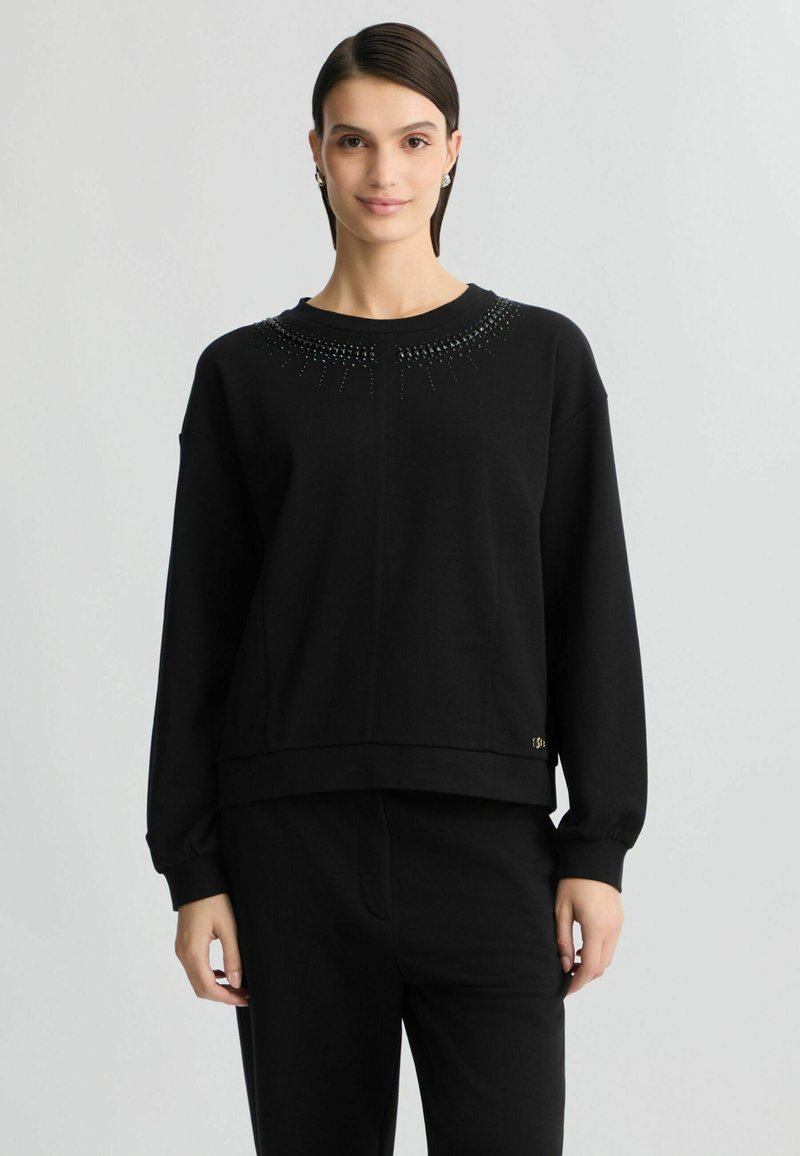 Zwarte pullover sweatshirt met een ronde hals, versierd met kraaldetails op de schouders, gemaakt van een zachte stof met een relaxte pasvorm.