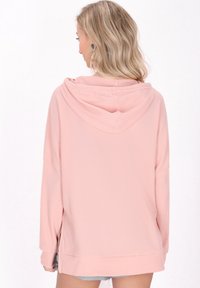 Felpa rosa a maniche lunghe con un motivo a maglia waffle strutturato, dotata di tasca frontale a marsupio e una vestibilità rilassata.