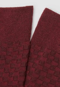 Burgundy sokker med et tekstureret ternet mønster ved anklen og ribbede manchetter, lavet af strikket stof med en blød finish.