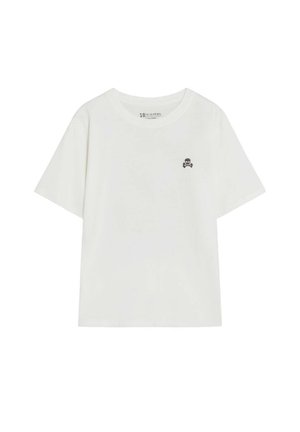 Camiseta blanca de manga corta con pequeño logo negro de calavera y huesos cruzados en el lado izquierdo del pecho, cuello redondo y ajuste holgado.