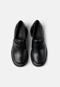 Black leather loafers with a smooth texture, rounded shape, and a wide strap across the vamp. Features subtle branding on the insole.