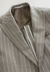 Light gray blazer with vertical pinstripes, textured wool fabric, notched lapels, and a brown lining featuring a subtle houndstooth pattern.