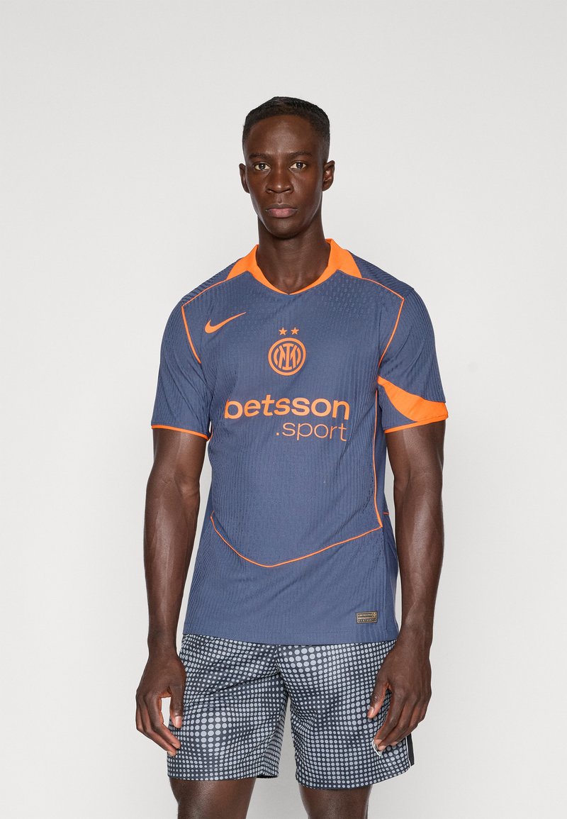 Nike sportsdrakt i mørkeblått med oransje detaljer, med rund krage, korte ermer, teksturert stoff, logo og sponsortekst.