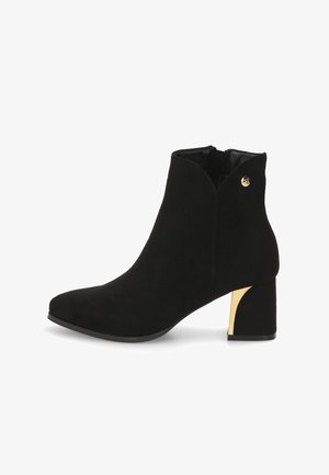 Botín negro de ante con punta afilada, tacón grueso acentuado en dorado y un diseño simple. Cuenta con una cremallera lateral para facilitar su uso.