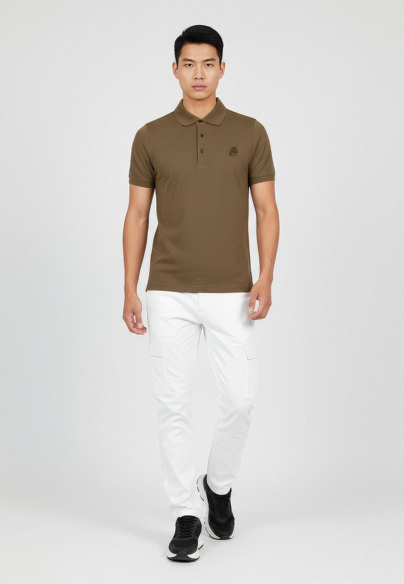 Camisa polo marrón de manga corta y cuello, combinada con pantalones cargo blancos. El conjunto presenta un diseño minimalista y sin patrones visibles.