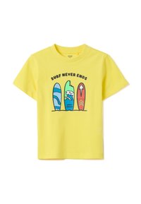 Camiseta de algodón amarilla con un gráfico de cuatro tablas de surf en azul, verde y rojo, con el texto "SURF NUNCA TERMINA" arriba.