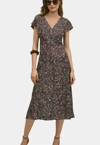 Sukienka w kwiatowy wzór z dekoltem w kształcie litery V, krótkimi falbanistymi rękawami i długości midi. Wykonana z lekkiego materiału w kolorach granatowym, pomarańczowym i kremowym.