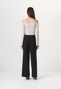 Haut à manches longues décolleté en gris clair associé à un pantalon large noir. Tissu doux, taille élastique et tons neutres.