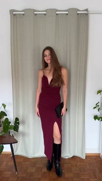 Bordo spalvos suknelė su gilia V formos iškirpte ir surinkta liemeniu, su šlaunies aukščio skeltuku. Derinama su juodais, iki kelių siekiančiais batais ir juoda delninuke.