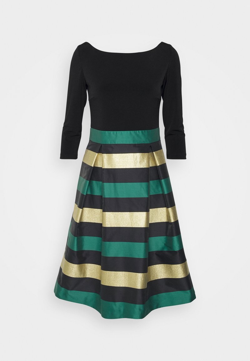 Haut noir à manches trois-quarts, se transformant en une jupe plissée avec des rayures horizontales vertes, dorées et noires.