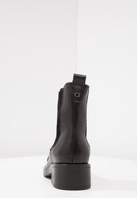 Bottine noire en cuir lisse avec des panneaux latéraux élastiques et un bout arrondi. Équipée d'un petit talon carré et d'une languette à l'arrière.