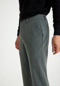 Grijze op maat gemaakte broeken met een subtiele textuur, voorzien van een vlakke voorkant, zijzakken en een knoopsluiting. Slim fit ontwerp.