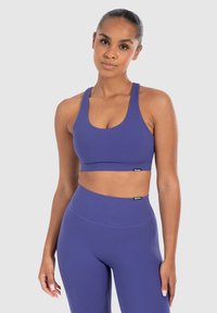 Paarse sportbh en hoge taille leggings gemaakt van rekbaar materiaal, met een aansluitend design en subtiele branding aan de zoom.