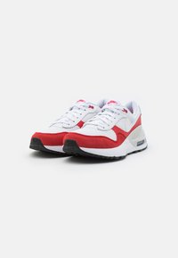 Scarpe atletiche rosse e bianche con una tomaia in rete e suede, dotate di un'unità di ammortizzazione visibile, lacci piatti e una suola nera testurizzata.