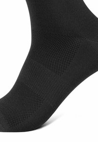 Sort strømpe med ribbet design og glatte sektioner samt strukturerede accenter. Materialet er blødt og elastisk, hvilket sikrer en tætsiddende pasform.