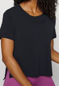 Camiseta negra de manga corta con cuello redondo y corte relajado. El material parece suave y liso con un corte ligeramente holgado.