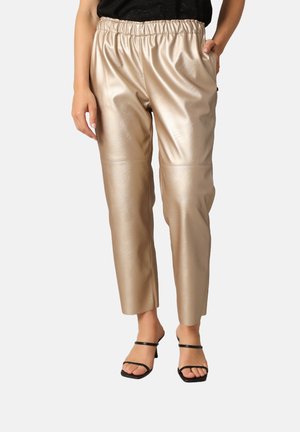 Pantalons en simili cuir beige avec une taille élastique, deux poches latérales, une coupe décontractée et un design de jambe fuselée. Texture simple avec des coutures minimales.