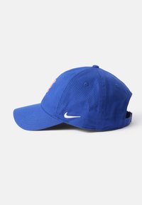 Modrá bavlnená čiapka s prehnutým šiltom, na prednej strane má oranžové logo a biely Nike swoosh na boku. S nastaviteľným zadným pásikom.