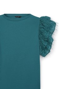 T-shirt teal avec une manche froncée douce et texturée en tissu transparent. Col rond et coupe standard.