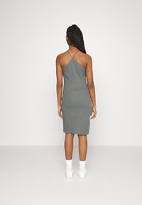 Szara, dopasowana sukienka midi na cienkich ramiączkach z tyłem w średnim kroju, wykonana z gładkiego, elastycznego materiału. Połączona z białymi sneakerami.