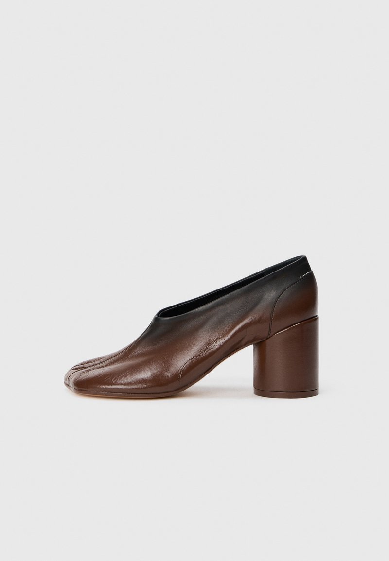 Scarpa da donna in pelle marrone con tacco a blocco arrotondato e punta leggermente appuntita, presentata su uno sfondo bianco semplice.