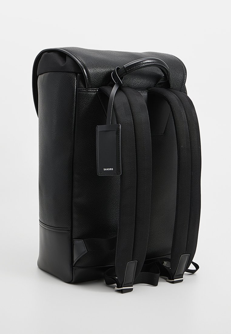 Schwarzer Leder-Rucksack mit strukturiertem Stoff, oberem Griff, verstellbaren schwarzen Riemen und einem rechteckigen Anhänger auf der Rückseite. Glatte Bodenausführung.